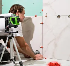 Installer using a laser level to align wall tile