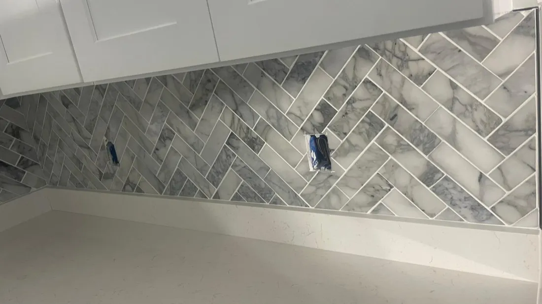 Close-up detail of herringbone marble backsplash tile pattern