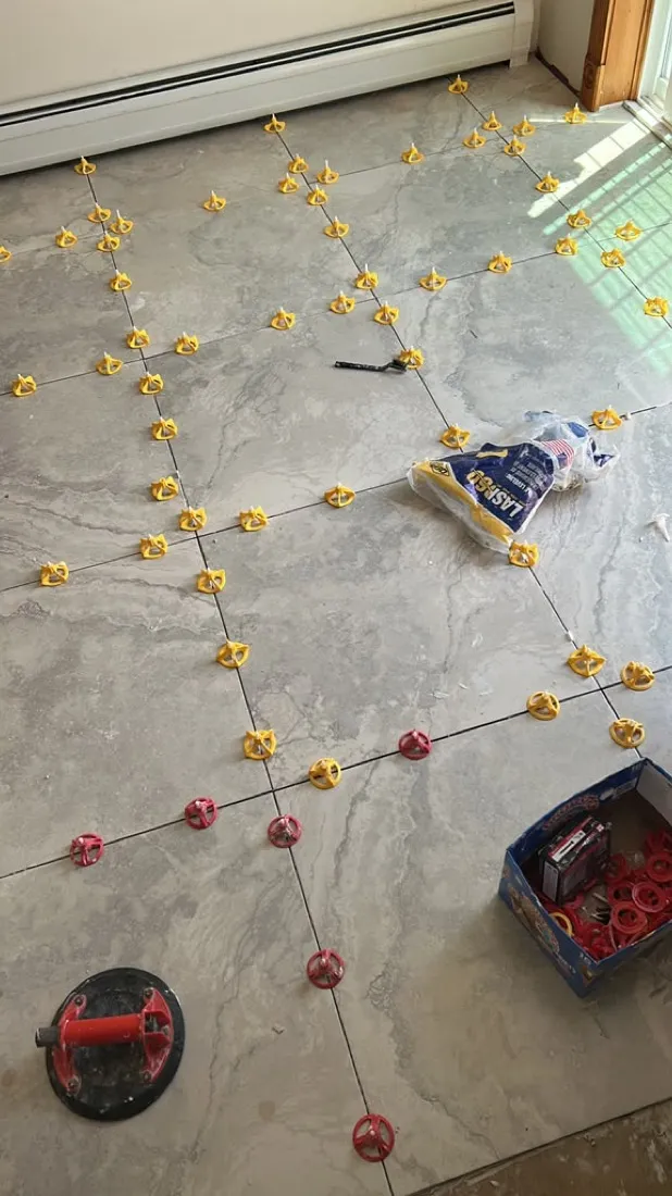 Tile flooring installation in progress with leveling spacers